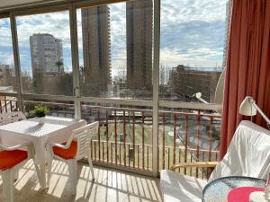 a balcony with a table and chairs and a large window at La Oca - Aloturin Benidorm in Benidorm