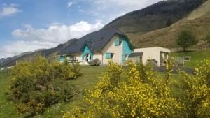 a house in a field with mountains in the background at Gîte de montagne du Plateau de Lhers in Accous