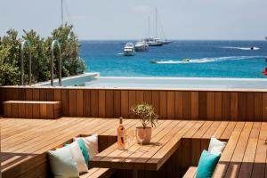 a wooden deck with a table and a view of the water at Mykonos Dove Beachfront Hotel in Platis Gialos
