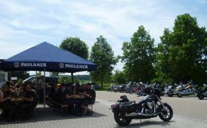 um grupo de pessoas sentadas sob uma tenda azul com uma moto em Landgasthof Zur Linde em Riedenburg