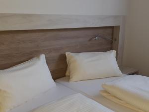 ein Bett mit zwei weißen Kissen und einem Kopfteil in der Unterkunft Landgasthof Zur Linde in Riedenburg