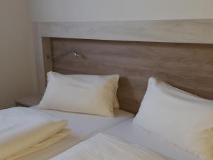 a bed with white pillows and a wooden headboard at Landgasthof Zur Linde in Riedenburg