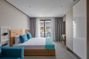 a bedroom with a bed and a blue chair at Albatros Luxury Suites in Nea Vrasna