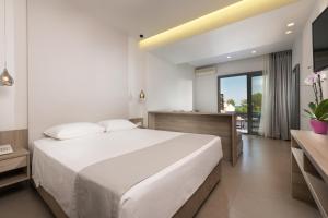 a bedroom with a large white bed and a bathroom at Princess Golden Beach Hotel in Chrysi Ammoudia