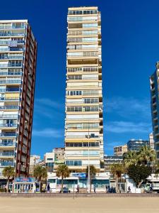 ベニドルムにあるMiramar Playa - Aloturin Benidormの浜辺のヤシの木が立ち並ぶ高層ビル