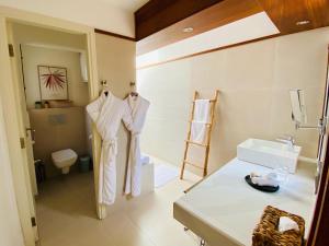 ein Badezimmer mit weißen Bademänteln und einem Waschbecken in der Unterkunft BOMA LifeStyle Hotel in Dakar