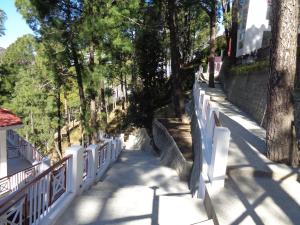Himalayan Splendour Resort في دانولتي: سور أبيض بجانب رصيف به أشجار