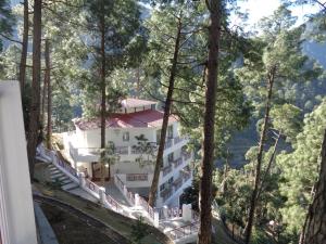 a white building on a hill in the woods at Himalayan Splendour Resort in Dhanaulti