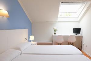 1 dormitorio con 2 camas blancas y ventana en Balneario Hotel Dávila, en Caldas de Reis