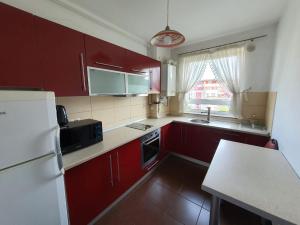 uma cozinha com armários vermelhos e um frigorífico branco em Apartment Richy Brasov em Braşov