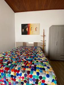 a bedroom with a colorful bed with a painting on the wall at Duas suítes no centro in São Bento do Sapucaí