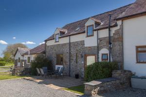 Casa de piedra con patio, mesa y sillas en Yr Wyddfa Cottage Anglesey, en Llanfairpwllgwyngyll