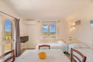 una camera con due letti e un tavolo e una finestra di Residence Hotel Lu Nibareddu a San Teodoro