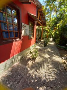 a red house with a pathway next to a building at Okakoaras Hotel in Maria Farinha