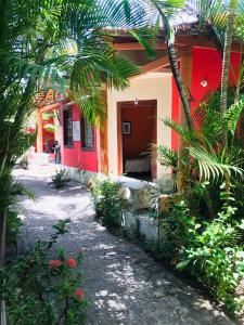 czerwono-biały dom z palmami przed nim w obiekcie Okakoaras Hotel w mieście Maria Farinha