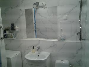 Baño blanco con lavabo y aseo en Lori Apartment, en Narva