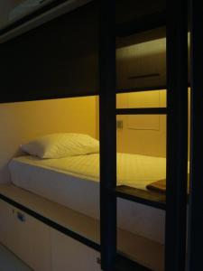 Bali Caps Hostel by Xhosteller في كوتا: غرفة نوم مع سرير بطابقين مع ملاءات بيضاء