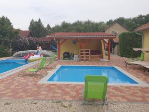 a swimming pool with chairs and a gazebo at Ponty Orsó Vendégház in Nagybaracska