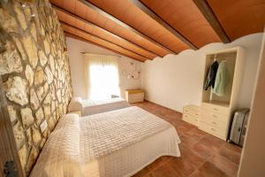 a bedroom with two beds and a stone wall at Casa Rural Casa Las Flores in Tíjola