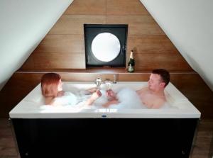 Ein Mann und eine Frau sitzen in einer Badewanne in der Unterkunft Les Béthunoises Centre Grand-Place - Spa et Sauna in Béthune
