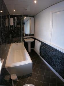 a bathroom with a bath tub and a sink at Strands Hotel/Screes Inn & Micro Brewery in Nether Wasdale +35 photos