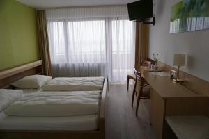 a hotel room with two beds and a desk at RUTHMANN-Rheinblick GARNI in Oestrich-Winkel