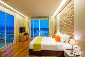 a bedroom with a large bed and large windows at Pattana Sports Resort in Si Racha