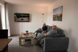 two men sitting on a couch in a living room at Hafen-Apartment Aurich in Aurich