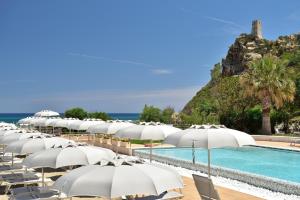 eine Reihe weißer Sonnenschirme neben einem Pool in der Unterkunft Hotel Club Torre Salinas - Adults Only in Muravera