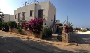 una casa blanca con flores rosas frente a una calle en Casa Vacanza Azzurra, en San Vito lo Capo