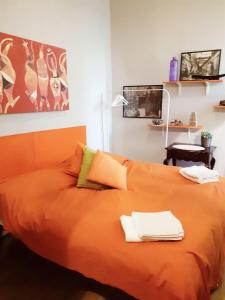 een slaapkamer met een oranje bed met handdoeken erop bij San Gregorio Studio in Napels