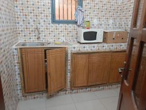 una cocina con fregadero y microondas en una encimera en Villa Chambre A climatisée douche Cuisine salon, en Bamako