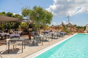 a swimming pool with tables and chairs next to a swimming pool at Residence Hotel Lu Nibareddu in San Teodoro