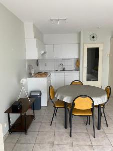 a kitchen with a table and chairs in a room at Appartement met aparte slaaphoek, garage en balkon in Middelkerke
