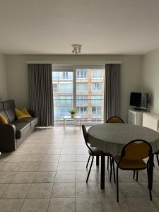 a living room with a table and chairs and a couch at Appartement met aparte slaaphoek, garage en balkon in Middelkerke
