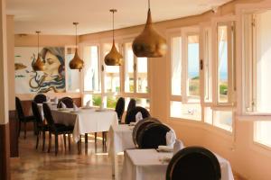 ein Restaurant mit weißen Tischen und Stühlen und Fenstern in der Unterkunft Hotel Patricia in Torreguadiaro