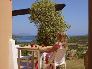 a woman sitting at a table with a drink at Residence Hotel Lu Nibareddu in San Teodoro
