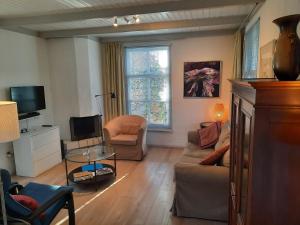 uma sala de estar com um sofá e uma televisão em Emmy's Cottage em Schoorl