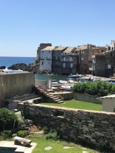 a stone wall with a view of the ocean and buildings at Studio pied dans l’eau CAP CORSE ERBALUNGA in Brando