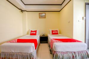 two beds in a room with red and white sheets at Super OYO 75385 Hotel Win Long in Bangkok