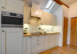a kitchen with white cabinets and a sink at Smithy Cottage in Berriew +8 photos