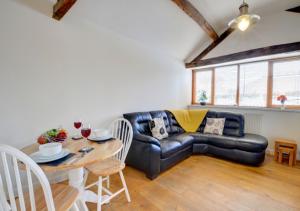 a living room with a leather couch and a table at Smithy Cottage in Berriew