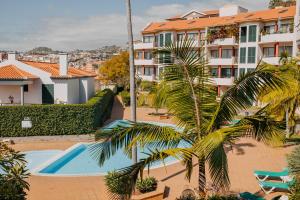 a palm tree in front of a building with a swimming pool at Funchal Lounge Apartment by Amazing Madeira in Funchal