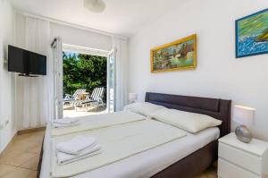 a white bedroom with a bed and a balcony at Seaside Guesthouse by JR City Apartments in Jadranovo