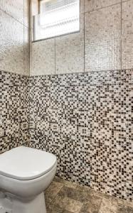 a bathroom with a toilet and a tiled wall at OYO Estrela Dalva, São Paulo in Sao Paulo