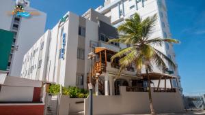 een gebouw met een palmboom ervoor bij Sandy Beach Hotel in San Juan