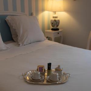a tray with cups and saucers on a bed at La Croix Blanche in Dax