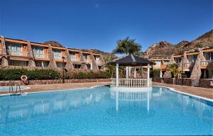 a swimming pool with a gazebo in front of a hotel at Villa Gisel in La Playa de Tauro