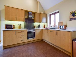 cocina grande con armarios y electrodomésticos de madera en Combine Shed en Bidford