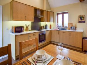 a kitchen with wooden cabinets and a table with a wine glass at Combine Shed in Bidford